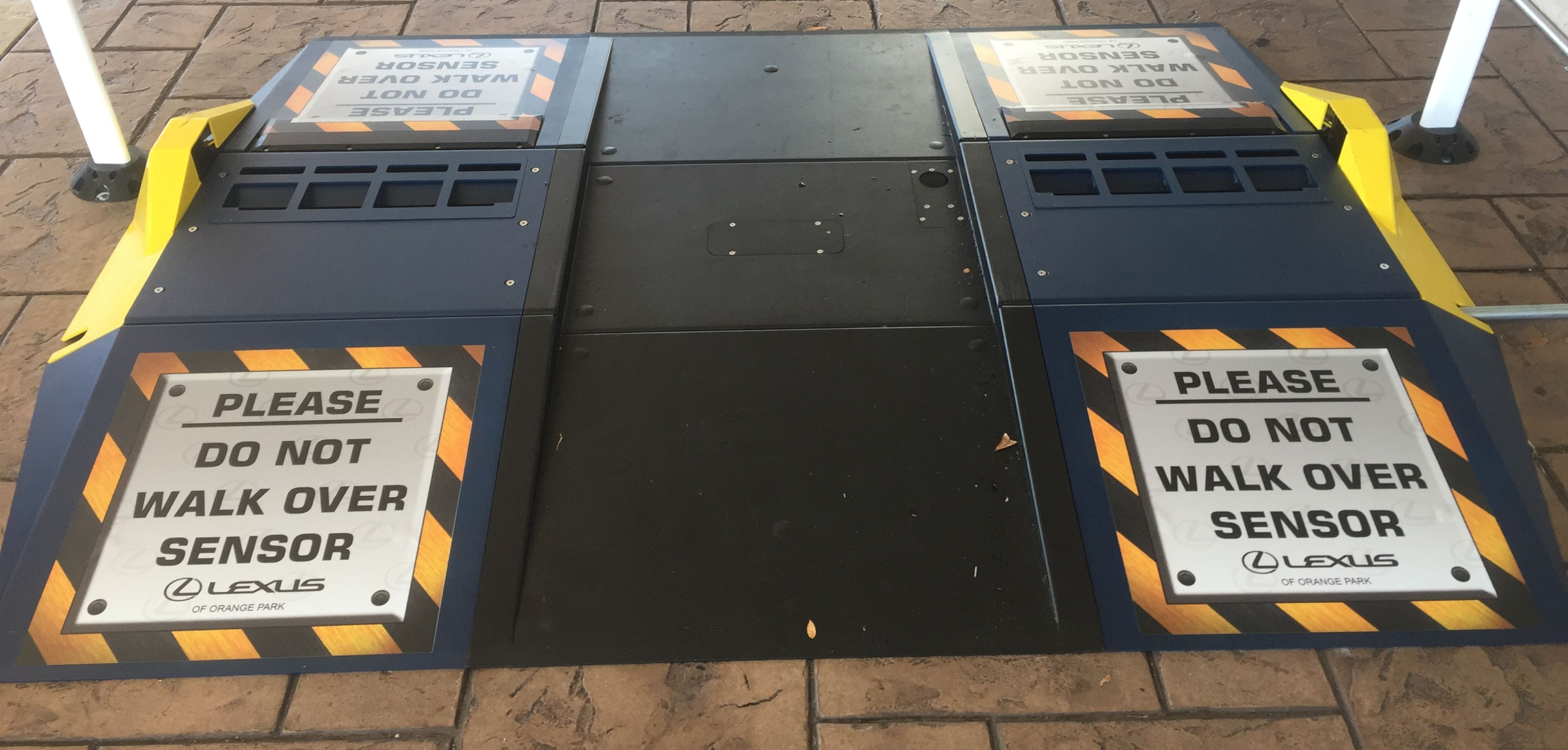 Two warning signs on a ground sensor area instructing not to walk over the sensor.