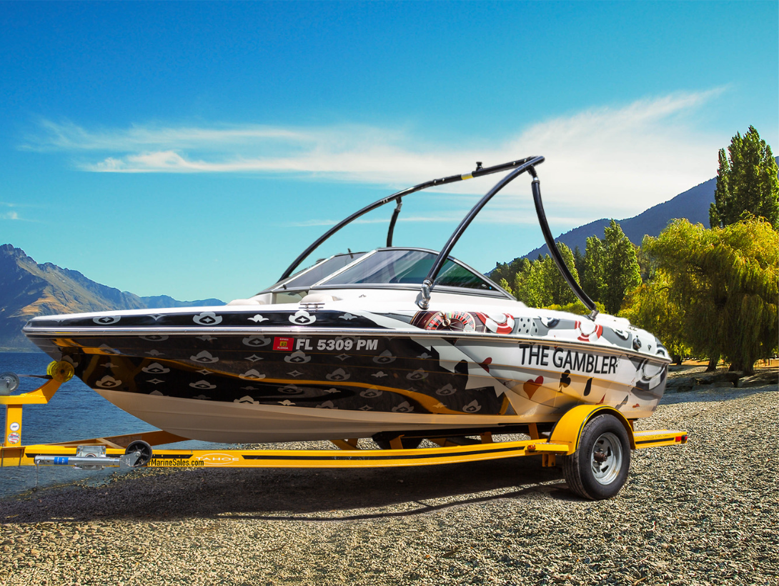 Full vinyl boat wrap on 16 foot on a speed boat being pulled by a yellow trailer with a lake and sky background. Boat wrap example from Wraps Direct located in Jacksonville, FL