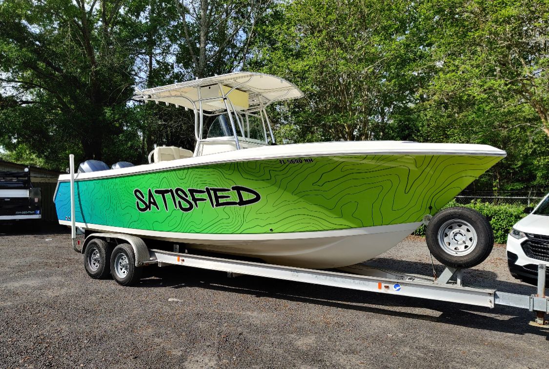 A lime green vinyl boat wrap design on a fishing boat being pulled by a trailer. A quality boat wrap leaves another customer satisfied at Wraps Direct in Jacksonville, FL