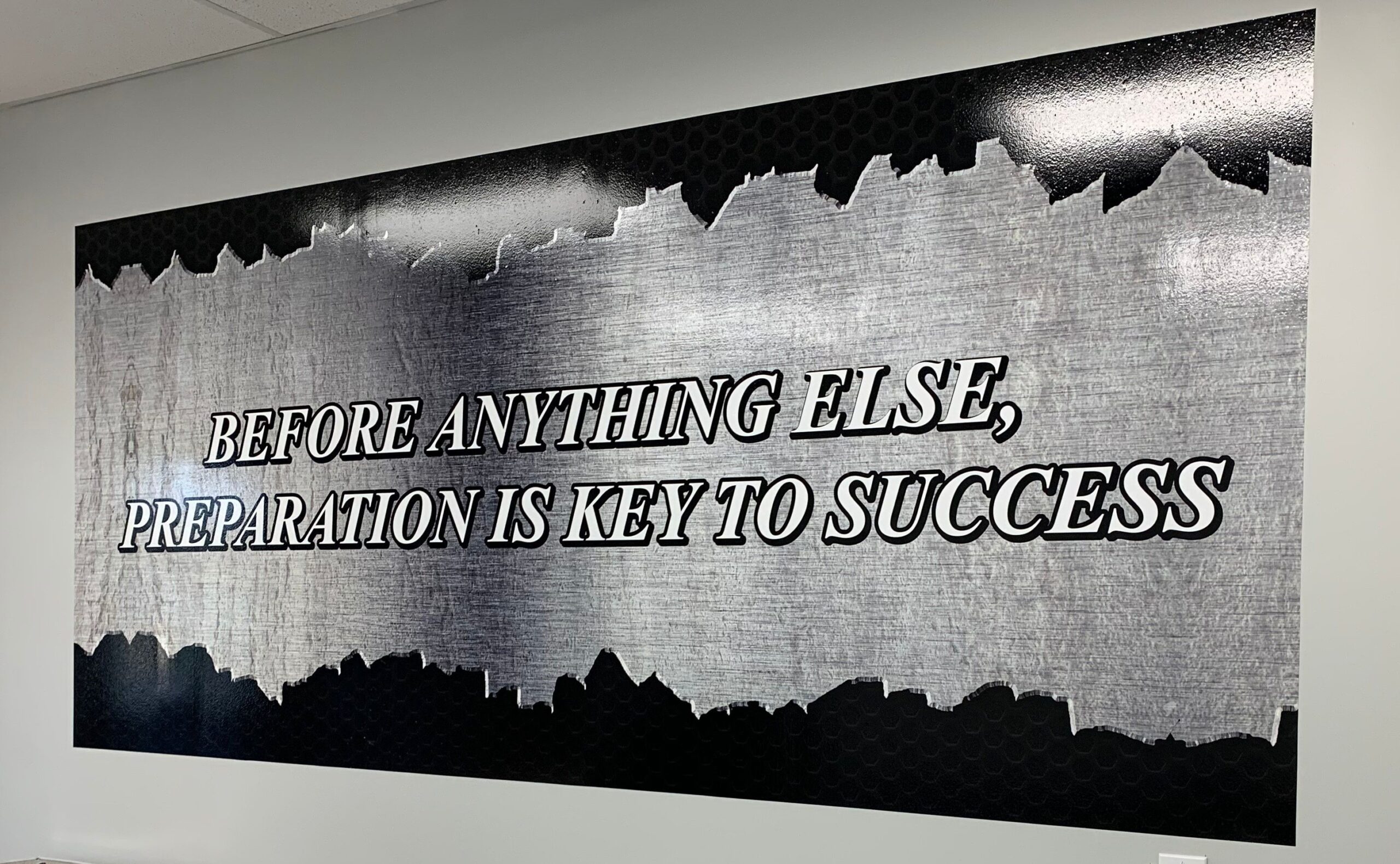 A custom glossy gray and black interior vinyl wall wrap that communicates a positive encouraging message, depicted on the inside wall of a home office building.
