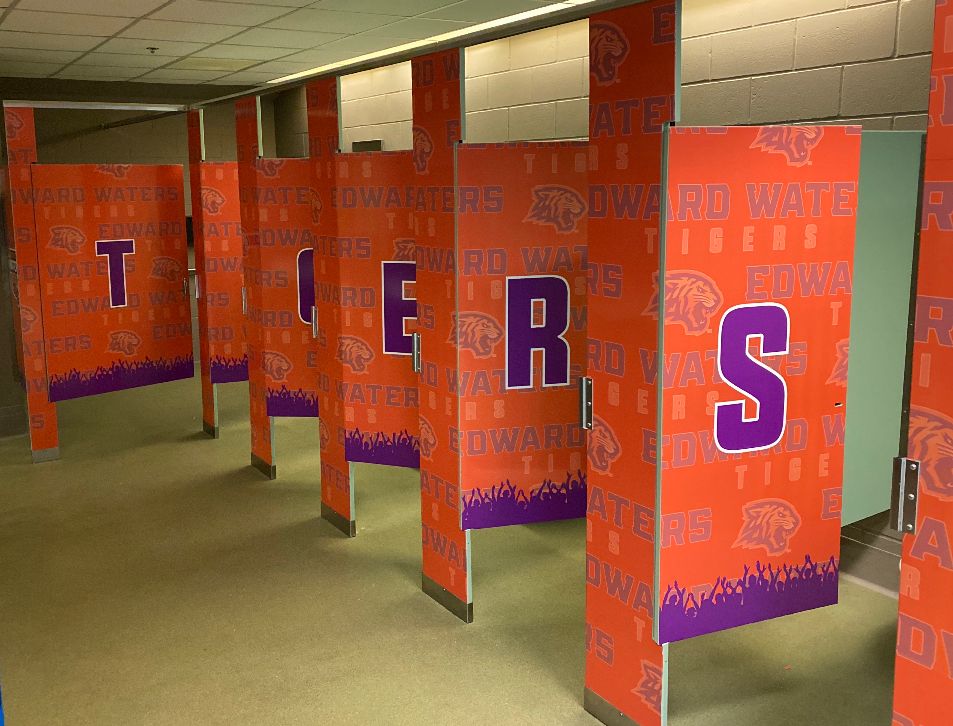 Interior custom orange and purple vinyl wall wrap depicted on the outskirts of a school's bathroom stall doors and privacy dividers that communicates the "Tigers" pride, and gets their students in the school spirit.